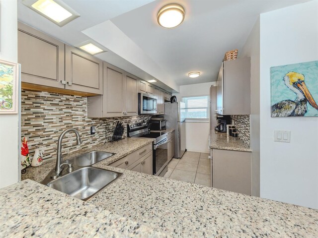 kitchen with light tile patterned flooring, gray cabinets, stainless steel appliances, and a sink