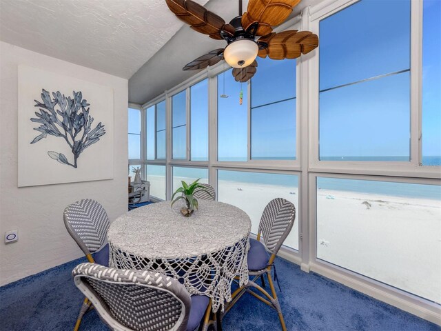 sunroom / solarium featuring a ceiling fan and a water view