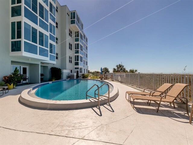 community pool with a patio and fence