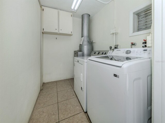 washroom with light tile patterned floors, cabinet space, and washer and clothes dryer