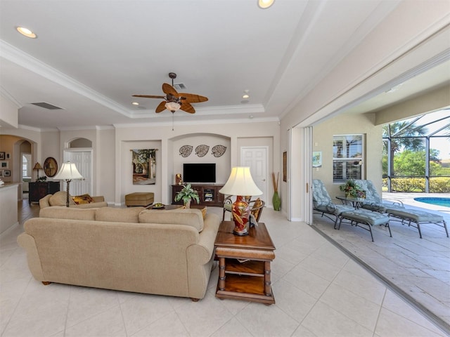 living room featuring a tray ceiling, arched walkways, and crown molding