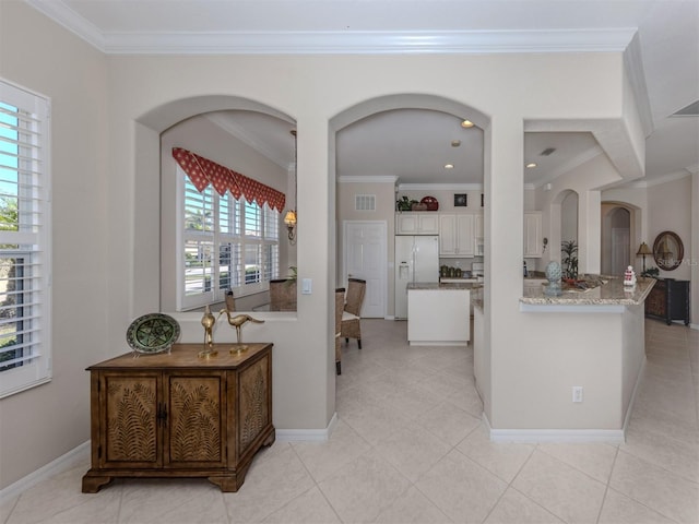 kitchen with white cabinets, visible vents, white fridge with ice dispenser, and ornamental molding