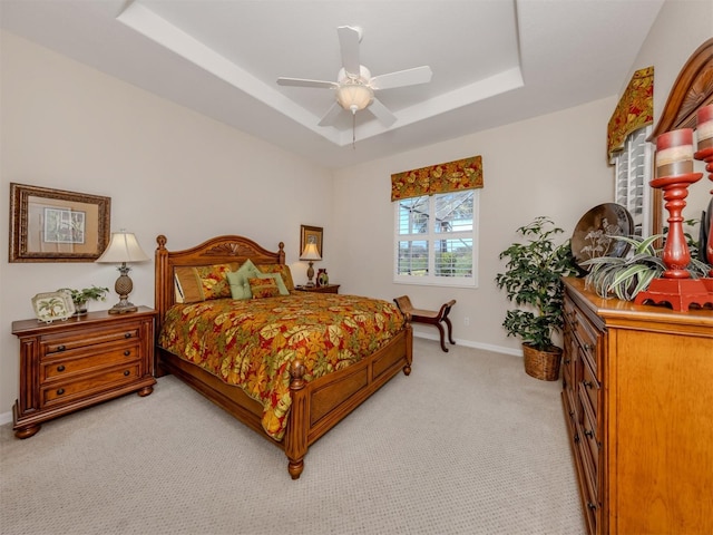 bedroom featuring ceiling fan, a raised ceiling, baseboards, and light carpet