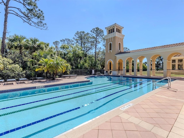 pool with a patio area and fence