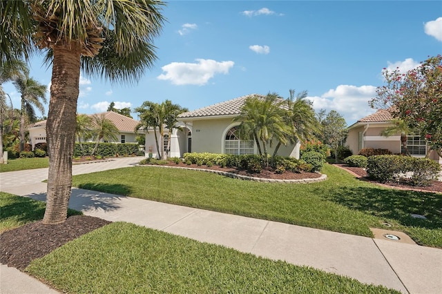 view of front of house with stucco siding, a tiled roof, and a front lawn