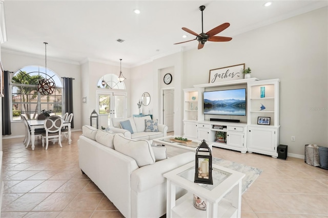 living area featuring light tile patterned flooring, baseboards, crown molding, and ceiling fan