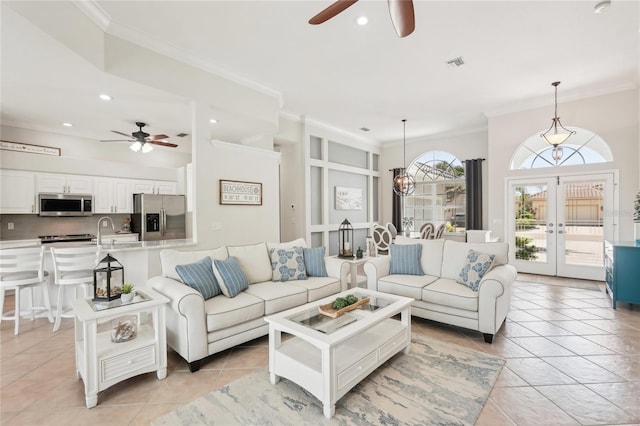 living area with light tile patterned floors, ceiling fan with notable chandelier, french doors, and ornamental molding