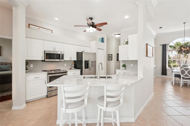 kitchen featuring a peninsula, a sink, ceiling fan, stainless steel appliances, and crown molding