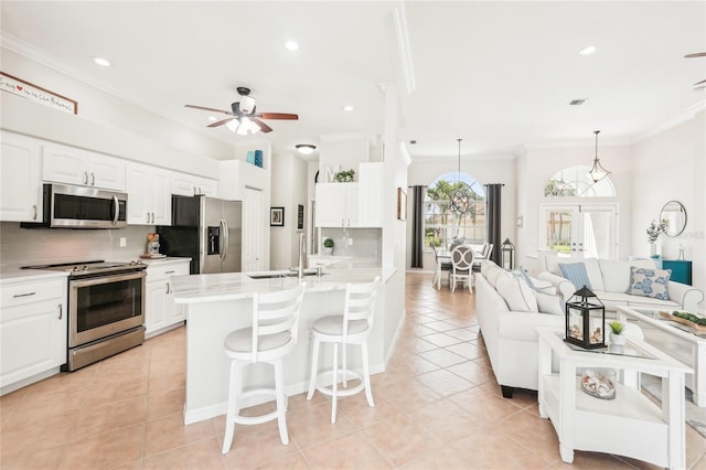 kitchen featuring ornamental molding, a sink, backsplash, appliances with stainless steel finishes, and a breakfast bar area