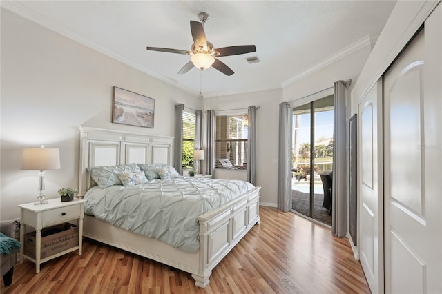 bedroom featuring visible vents, light wood-style floors, ornamental molding, and access to outside