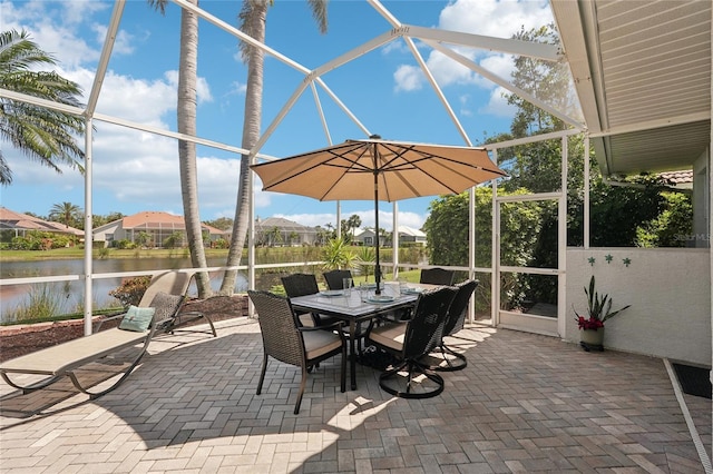 view of patio with glass enclosure, a water view, and outdoor dining space