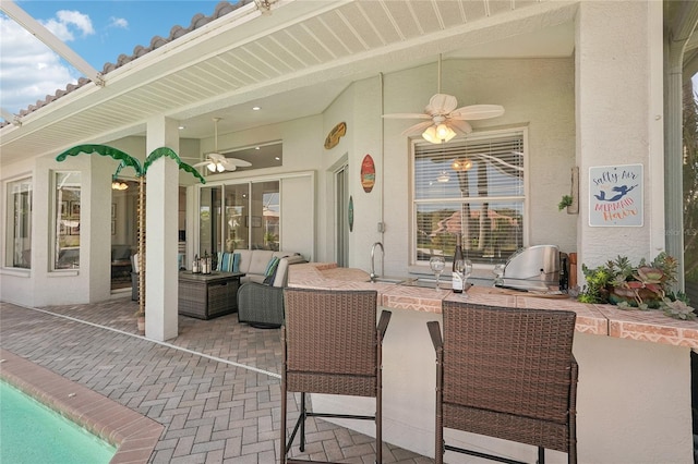 view of patio / terrace featuring an outdoor living space, outdoor wet bar, area for grilling, and ceiling fan