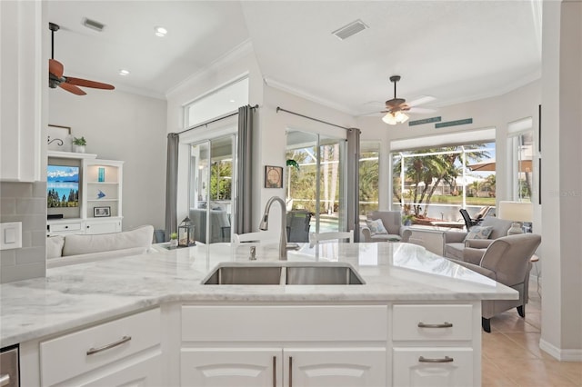 kitchen featuring ceiling fan, open floor plan, crown molding, and a sink