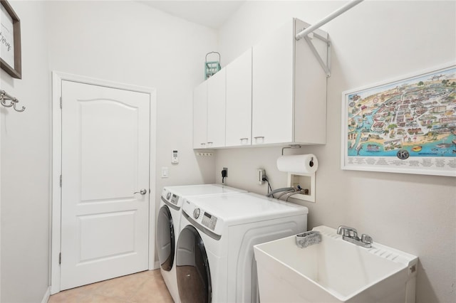 washroom with light tile patterned floors, washing machine and dryer, cabinet space, and a sink