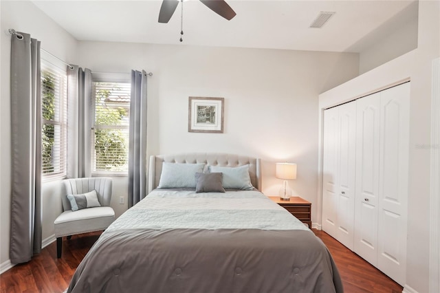 bedroom featuring a ceiling fan, dark wood-style floors, visible vents, baseboards, and a closet