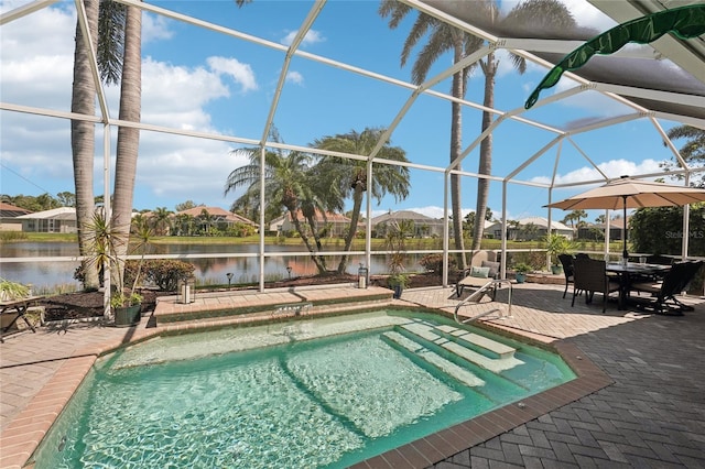 pool featuring glass enclosure, a patio, and a water view