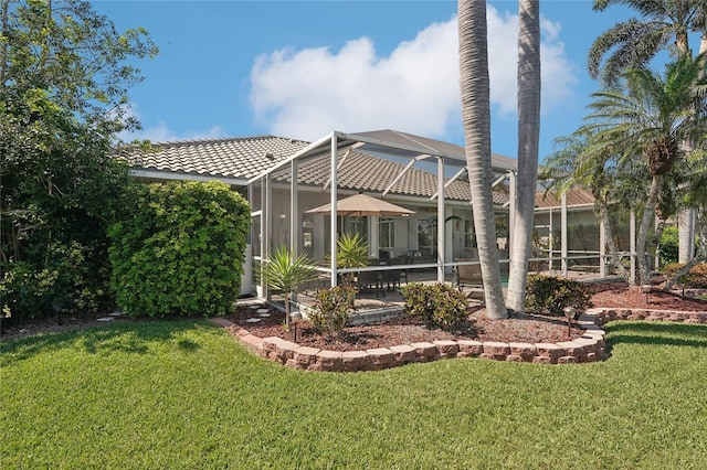 back of property with a lawn, a lanai, and a tiled roof