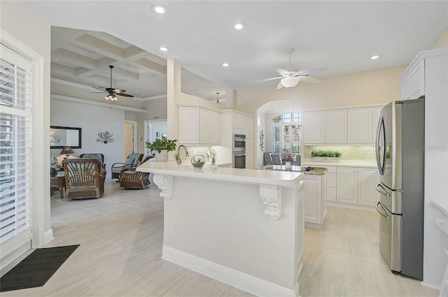 kitchen featuring ceiling fan, a peninsula, coffered ceiling, and stainless steel appliances