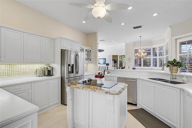 kitchen featuring a kitchen island, decorative backsplash, white cabinets, stainless steel appliances, and a sink