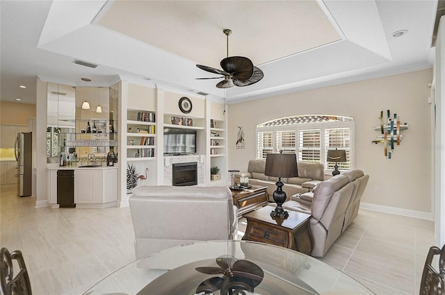 living room featuring a fireplace, a raised ceiling, a ceiling fan, and visible vents