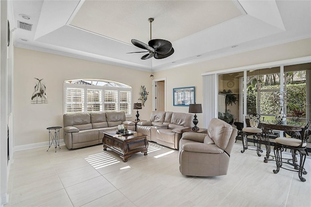 living room featuring a tray ceiling, baseboards, visible vents, and a ceiling fan