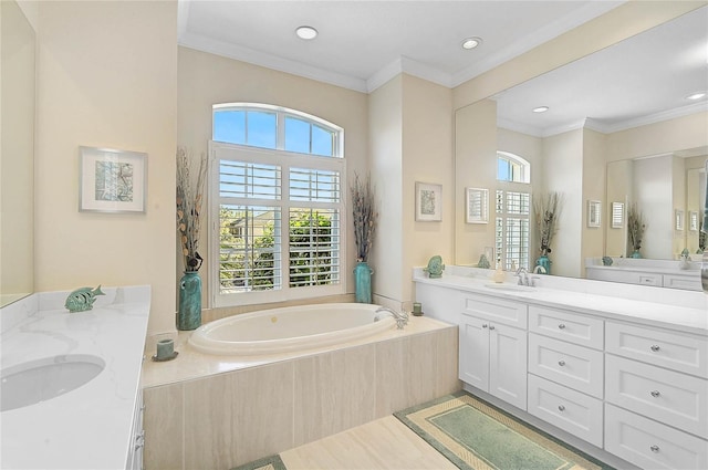 full bathroom featuring a garden tub, two vanities, crown molding, and a sink