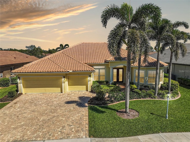 mediterranean / spanish house with french doors, a front lawn, an attached garage, and a tiled roof