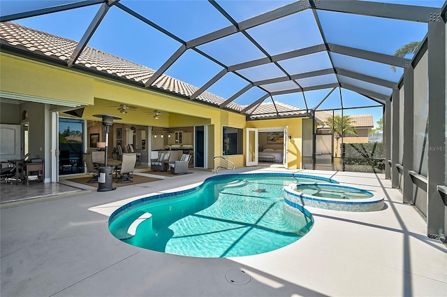 view of pool featuring a patio area, glass enclosure, and a pool with connected hot tub