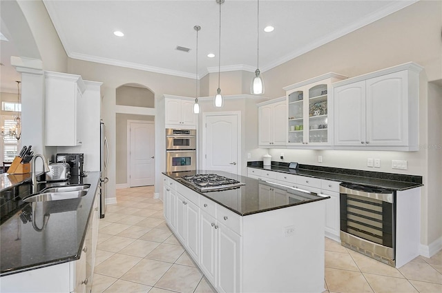 kitchen featuring a center island, beverage cooler, arched walkways, stainless steel appliances, and a sink