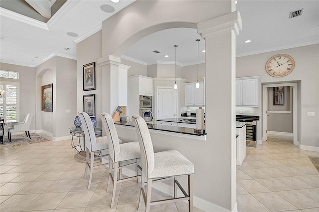 kitchen with light tile patterned floors, visible vents, ornate columns, arched walkways, and white cabinetry