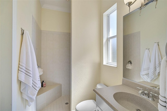 bathroom featuring vanity, crown molding, toilet, and tiled shower