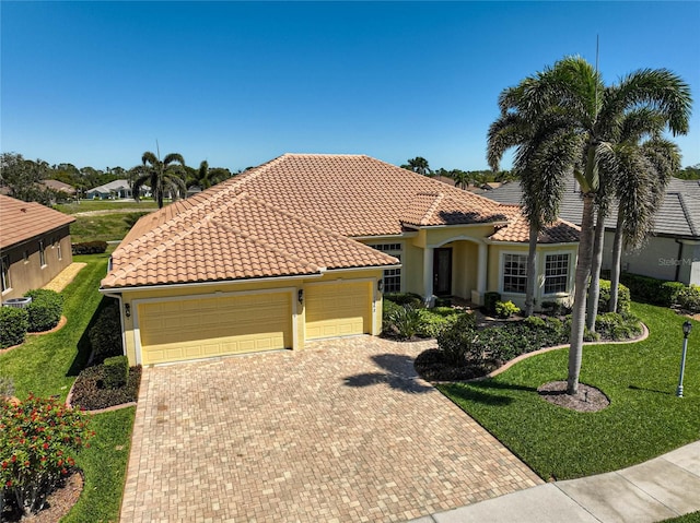 mediterranean / spanish-style home featuring a front yard, an attached garage, stucco siding, a tile roof, and decorative driveway