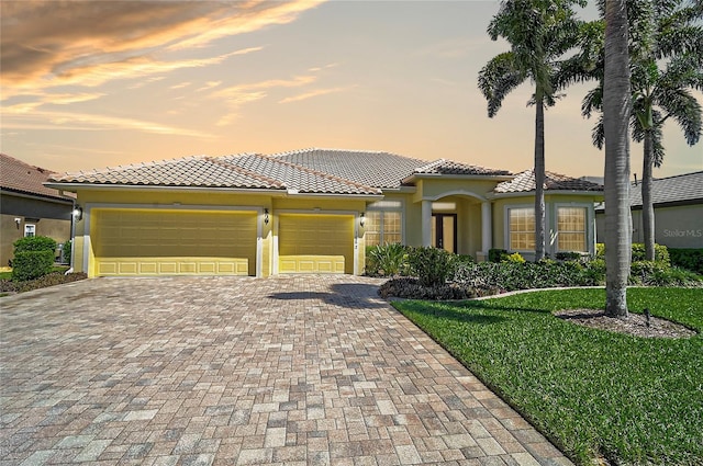 mediterranean / spanish-style house featuring stucco siding, decorative driveway, an attached garage, and a tile roof