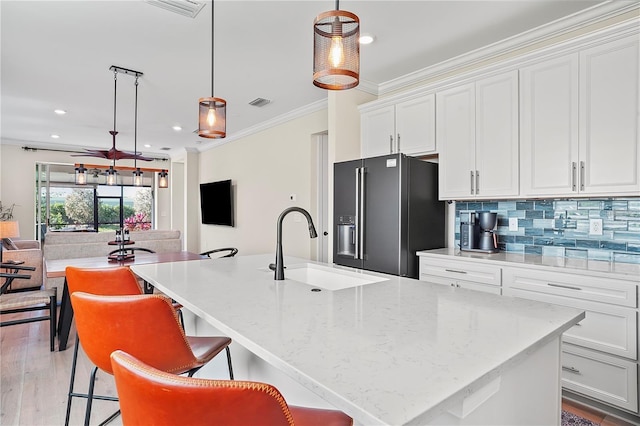 kitchen featuring white cabinets, a sink, backsplash, crown molding, and high end black fridge