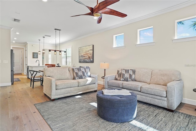 living area with crown molding, light wood-type flooring, baseboards, visible vents, and recessed lighting