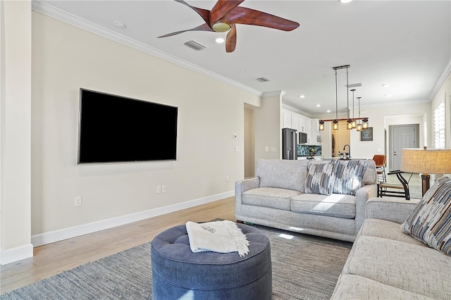 living room featuring baseboards, a ceiling fan, visible vents, and light wood-type flooring