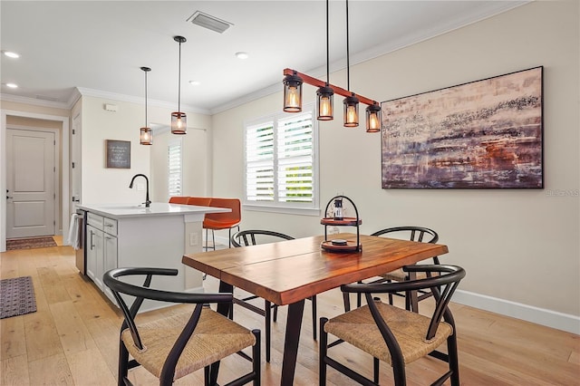 dining space featuring light wood finished floors, visible vents, and ornamental molding