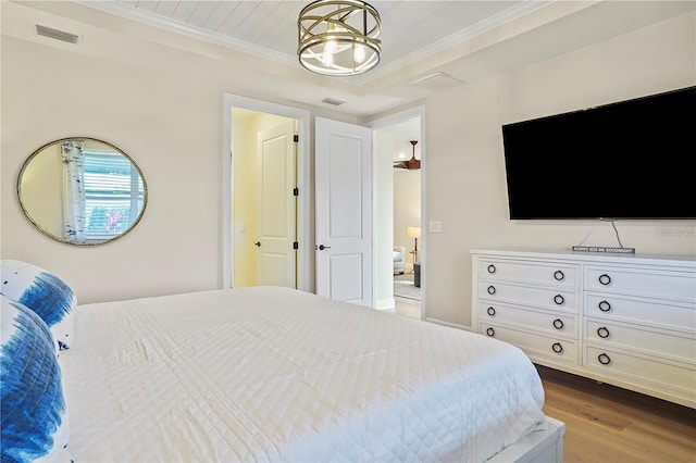 bedroom featuring wood finished floors, visible vents, a chandelier, and ornamental molding