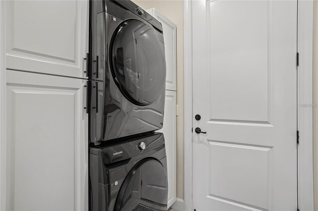 washroom with stacked washing maching and dryer and cabinet space