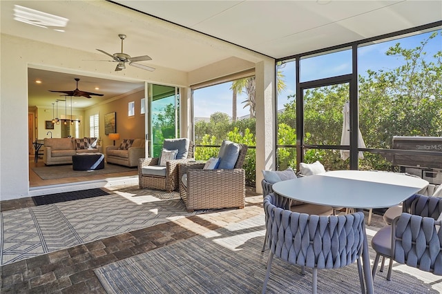 sunroom with ceiling fan, outdoor lounge area, and outdoor dining space