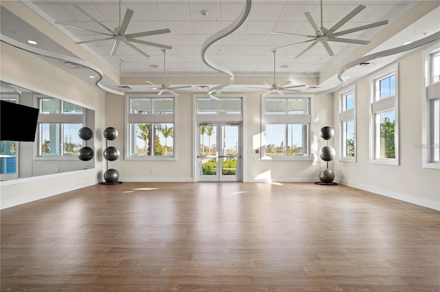 exercise area with baseboards, a ceiling fan, wood finished floors, and a healthy amount of sunlight