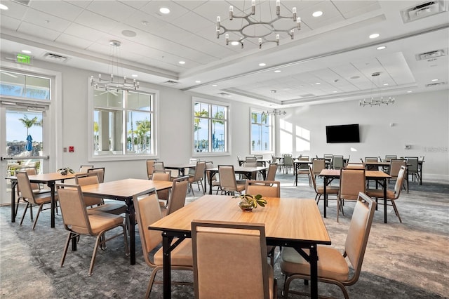 dining space featuring a raised ceiling, visible vents, and a notable chandelier