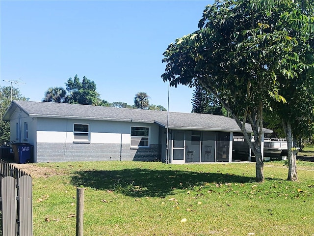 view of front facade with a front yard, brick siding, a sunroom, and stucco siding