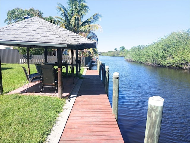 dock area with a gazebo, fence, a yard, and a water view