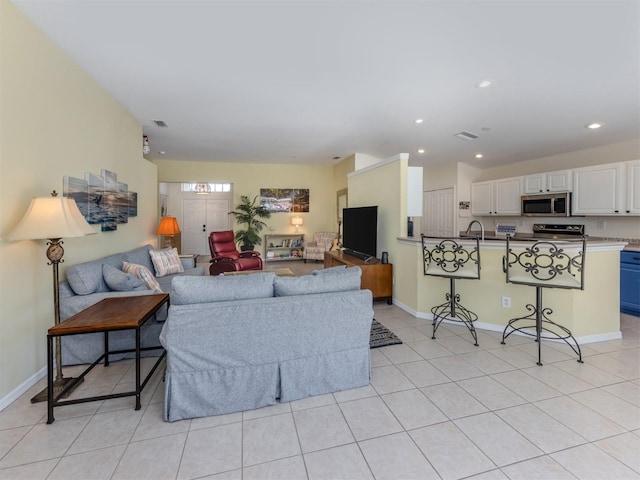 living room with light tile patterned floors, visible vents, baseboards, and recessed lighting