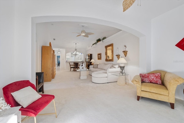 carpeted living room featuring lofted ceiling, ceiling fan with notable chandelier, and arched walkways