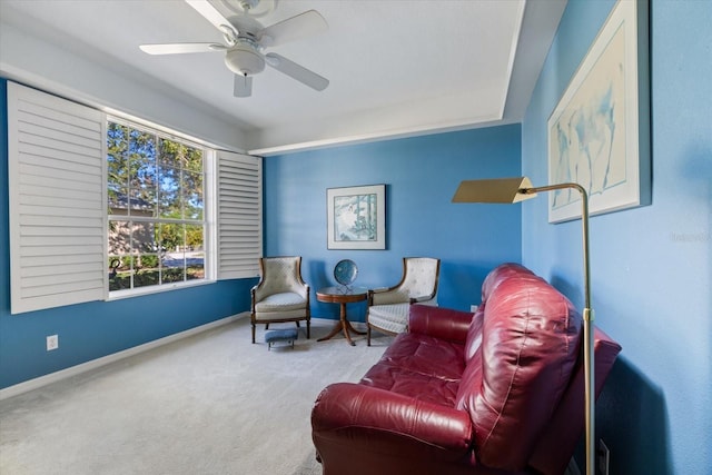 living area with carpet, baseboards, and ceiling fan