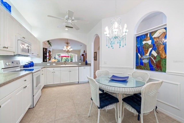 kitchen with light countertops, ceiling fan with notable chandelier, arched walkways, white cabinets, and white appliances