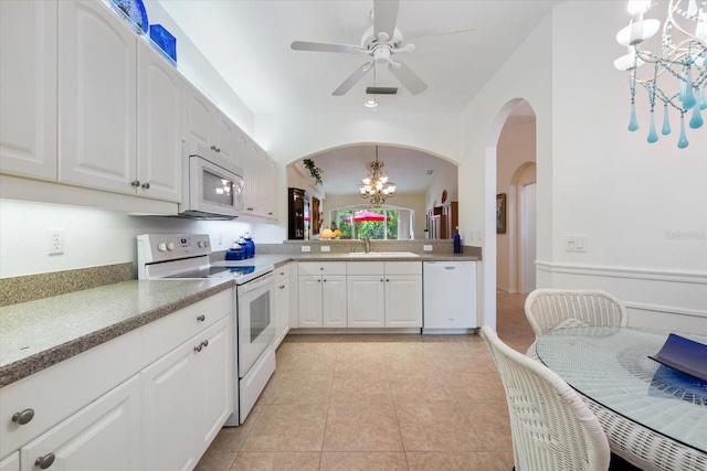 kitchen with white appliances, light tile patterned floors, a sink, white cabinetry, and decorative light fixtures