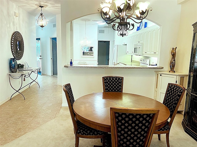 dining room with light tile patterned floors, baseboards, visible vents, arched walkways, and a chandelier